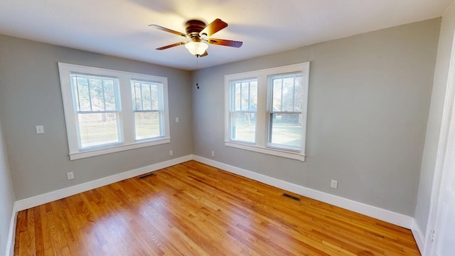 spare room with light wood-style flooring, visible vents, baseboards, and a ceiling fan