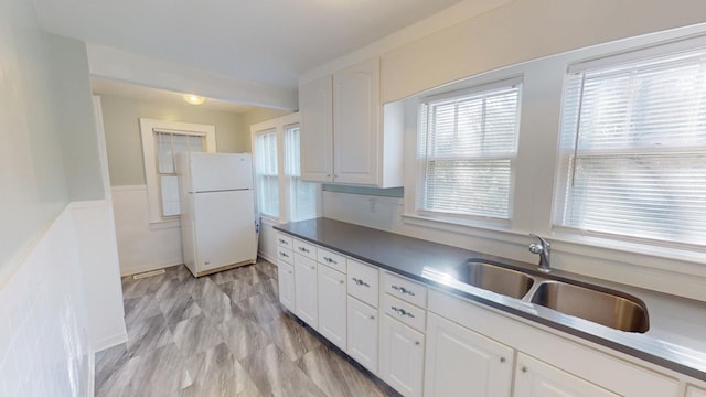 kitchen with decorative backsplash, white cabinets, a sink, and freestanding refrigerator