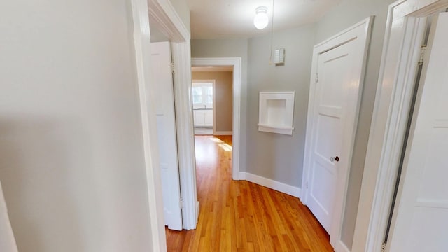 hallway featuring light wood-type flooring and baseboards