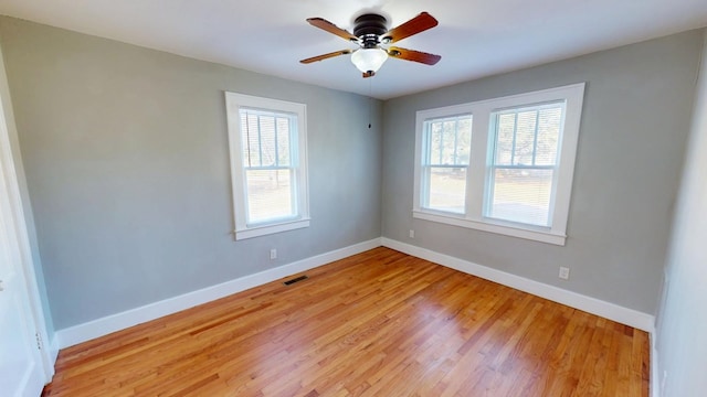 spare room with a ceiling fan, light wood-type flooring, visible vents, and baseboards