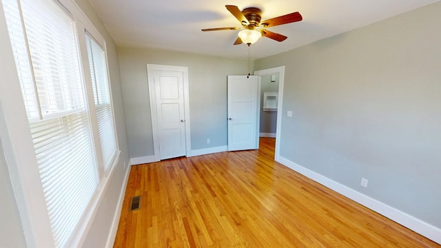 unfurnished bedroom featuring light wood finished floors, a closet, visible vents, a ceiling fan, and baseboards