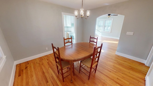 dining area featuring light wood-style flooring, baseboards, and arched walkways