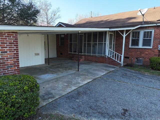 exterior space with a carport, crawl space, brick siding, and driveway