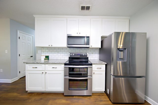 kitchen with appliances with stainless steel finishes, visible vents, baseboards, and tasteful backsplash