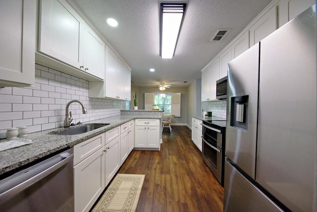kitchen featuring a peninsula, a sink, stainless steel appliances, white cabinetry, and visible vents