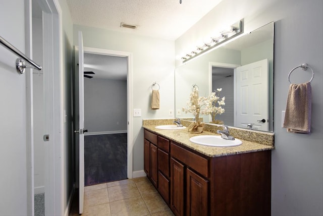 full bath with a textured ceiling, visible vents, a sink, and double vanity
