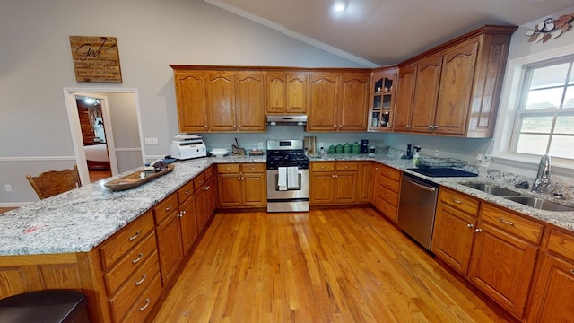 kitchen featuring sink, stainless steel appliances, light stone counters, ornamental molding, and light wood-type flooring