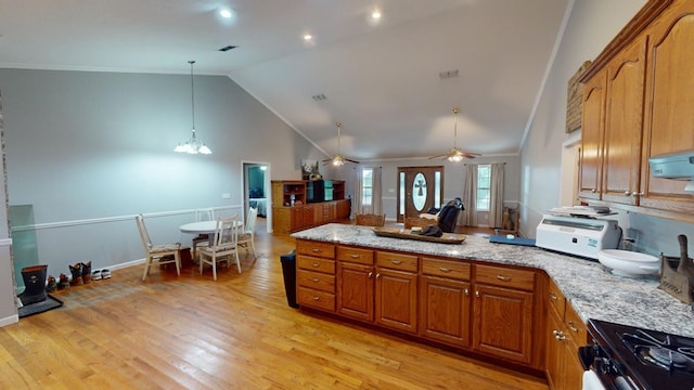 kitchen with ceiling fan with notable chandelier, pendant lighting, high vaulted ceiling, light stone countertops, and light wood-type flooring