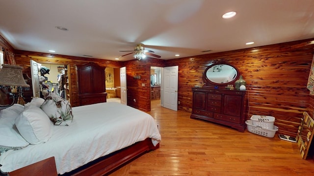 bedroom with wood walls, ceiling fan, and light wood-type flooring