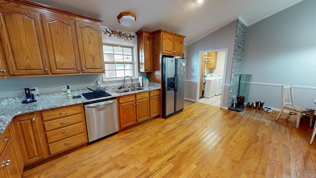 kitchen featuring vaulted ceiling, appliances with stainless steel finishes, light stone counters, independent washer and dryer, and crown molding