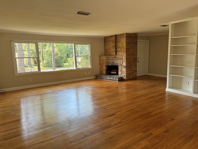 unfurnished living room featuring ornamental molding, hardwood / wood-style floors, and a fireplace