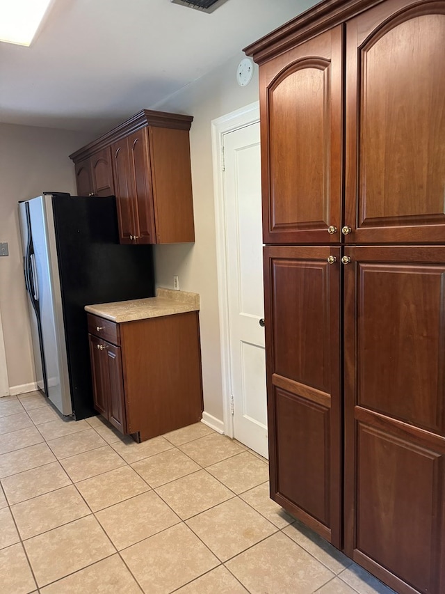 kitchen with light tile patterned flooring and stainless steel fridge