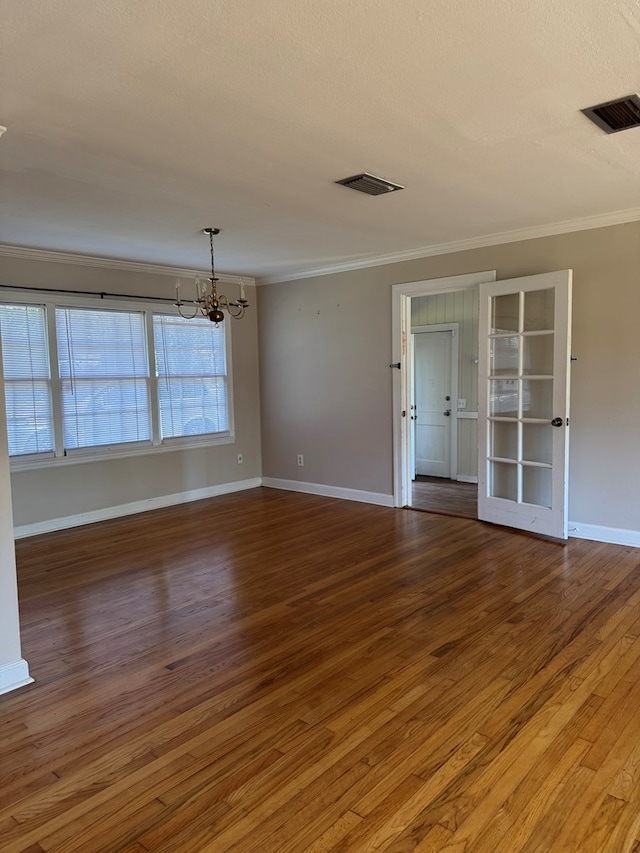 spare room with ornamental molding, dark hardwood / wood-style floors, a textured ceiling, and an inviting chandelier