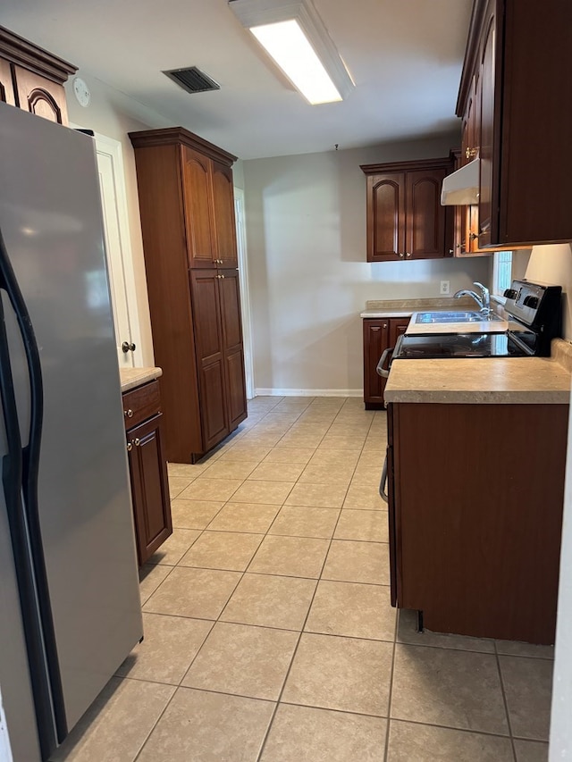 kitchen with appliances with stainless steel finishes, dark brown cabinets, and light tile patterned floors