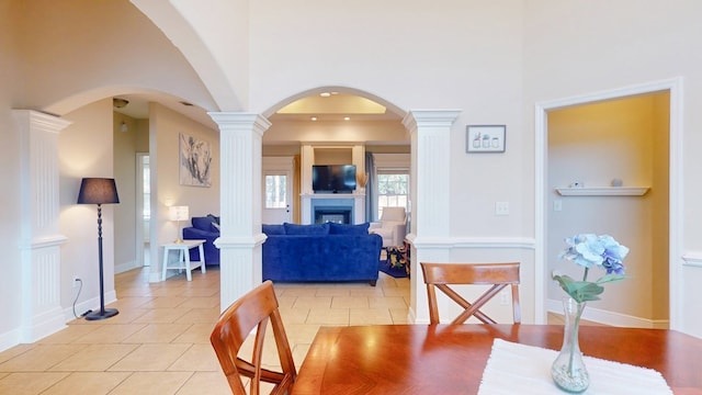 dining space with a towering ceiling, decorative columns, and light tile patterned flooring