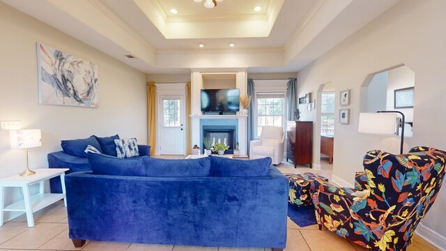 living room with ornamental molding, a raised ceiling, and light tile patterned floors