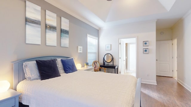 bedroom with crown molding, hardwood / wood-style flooring, and a raised ceiling