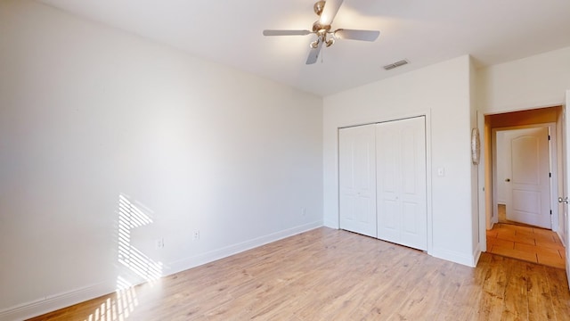 unfurnished bedroom featuring ceiling fan, light wood-type flooring, and a closet