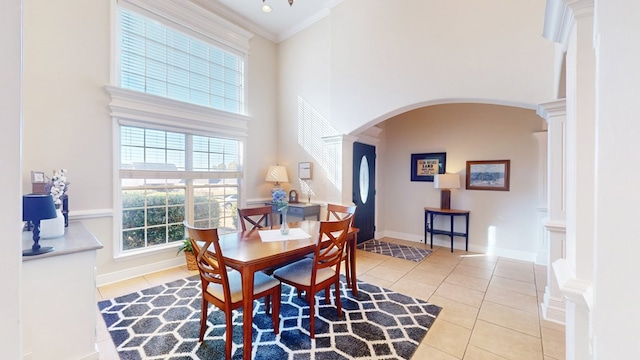 tiled dining area featuring crown molding and a high ceiling