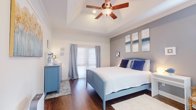 bedroom with ceiling fan, ornamental molding, a tray ceiling, and dark hardwood / wood-style flooring