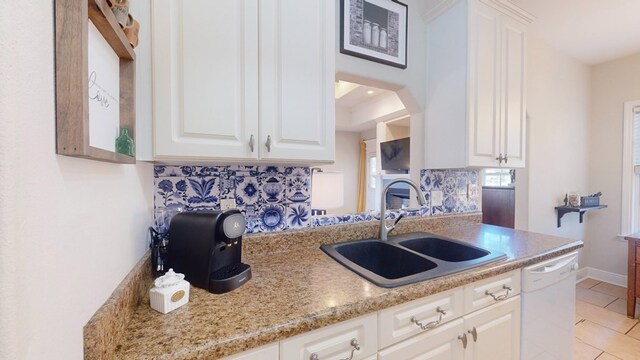 kitchen with white cabinetry, white dishwasher, sink, and backsplash