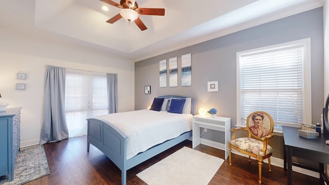 bedroom with dark hardwood / wood-style flooring, a raised ceiling, and ceiling fan