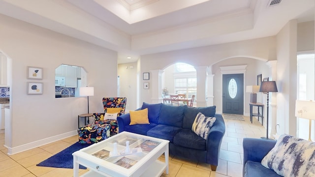 tiled living room featuring decorative columns, crown molding, and a tray ceiling