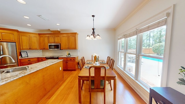 316 Bellingham Dr, Thomasville, GA 31792 - kitchen with stainless steel appliances, a chandelier, crown molding, hanging light fixtures, and light wood-style floors