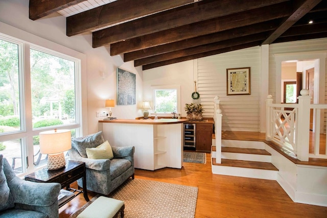 sitting room with wine cooler, vaulted ceiling with beams, light wood-type flooring, and a wealth of natural light