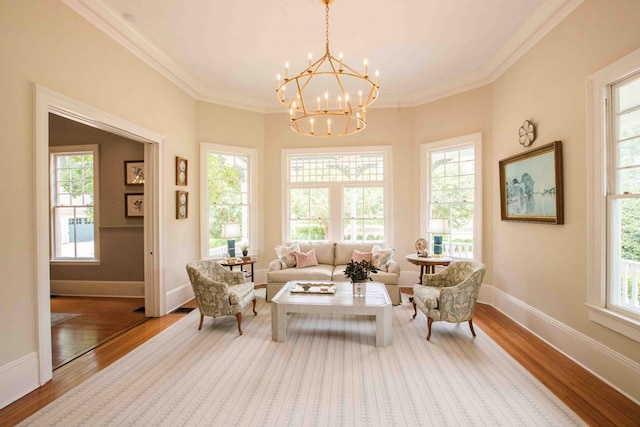 living area with hardwood / wood-style flooring, plenty of natural light, ornamental molding, and a chandelier