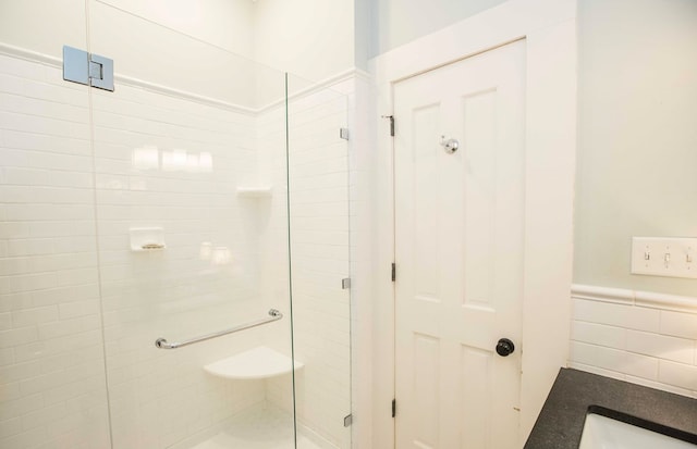 bathroom with a shower with door and tile walls