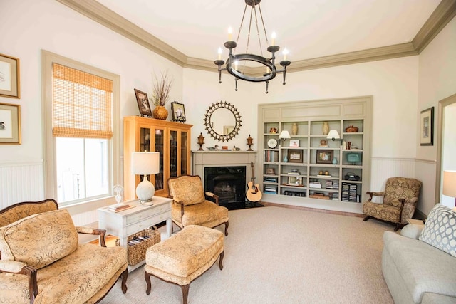 sitting room with a notable chandelier, carpet floors, ornamental molding, and a premium fireplace