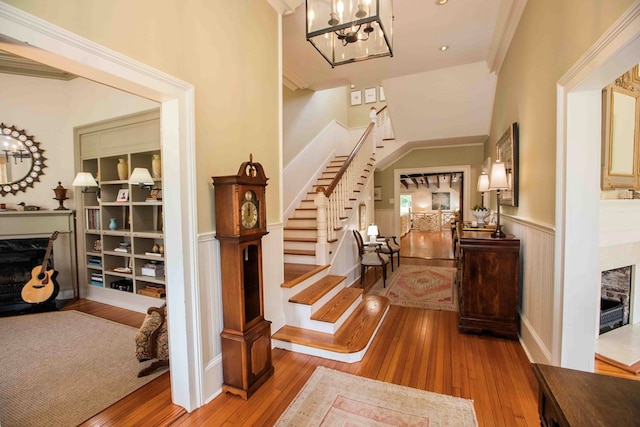 entryway featuring a premium fireplace, ornamental molding, a notable chandelier, and light hardwood / wood-style flooring