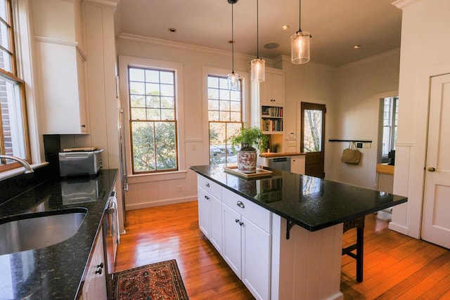 kitchen with dark stone countertops, crown molding, a breakfast bar area, and white cabinets