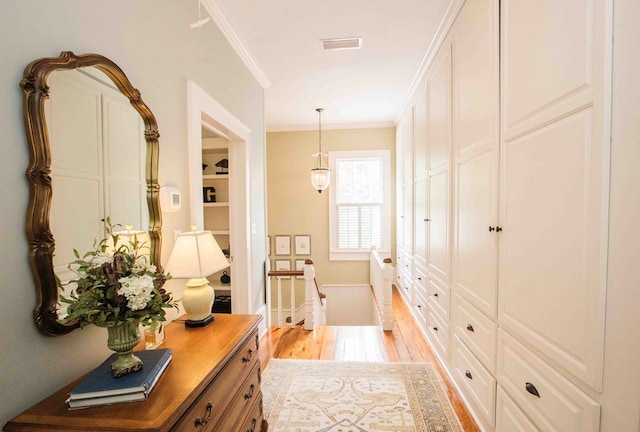 corridor with light hardwood / wood-style flooring and ornamental molding