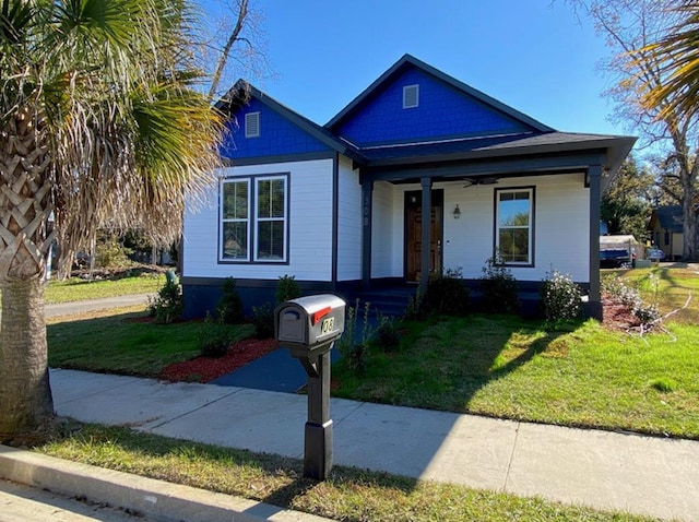 bungalow-style home featuring covered porch and a front lawn