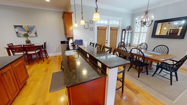 kitchen with a breakfast bar, sink, hanging light fixtures, and light hardwood / wood-style flooring