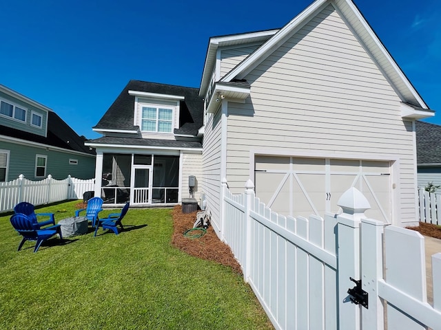 rear view of property with a yard, a sunroom, and a garage