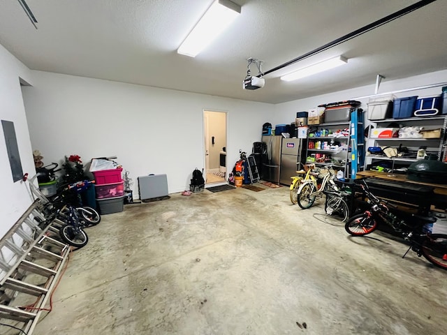 garage with a garage door opener and stainless steel fridge