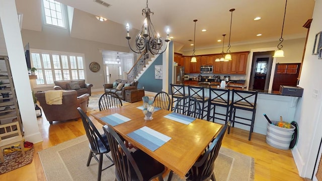 dining space with crown molding, light hardwood / wood-style flooring, and a chandelier