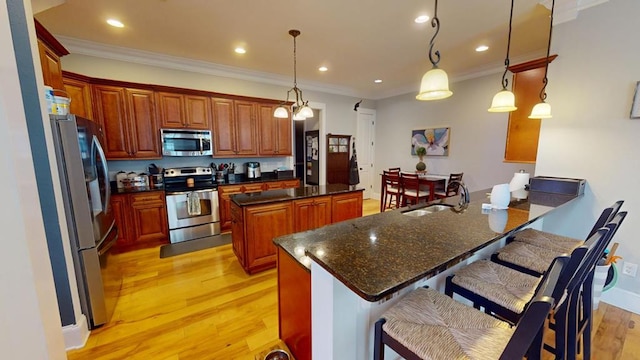 kitchen featuring a kitchen island, appliances with stainless steel finishes, a breakfast bar, and pendant lighting