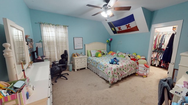 bedroom featuring a walk in closet, vaulted ceiling, light carpet, a closet, and ceiling fan