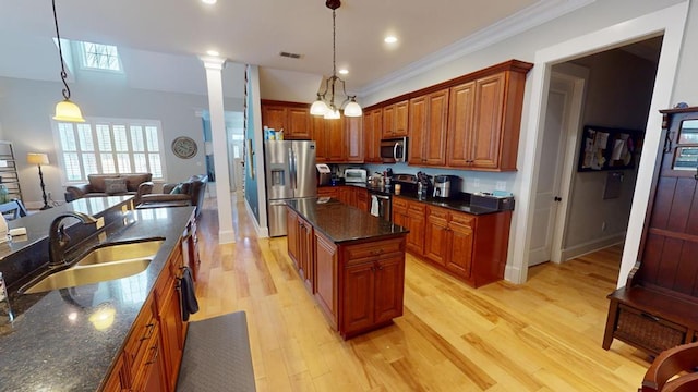 kitchen featuring stainless steel appliances, a kitchen island, sink, and decorative light fixtures