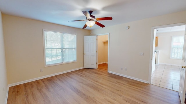 unfurnished bedroom with ceiling fan, a spacious closet, and light hardwood / wood-style floors