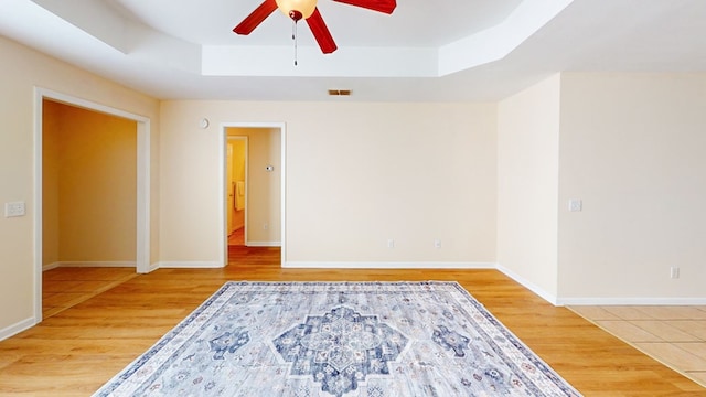 spare room featuring a tray ceiling, ceiling fan, and hardwood / wood-style flooring