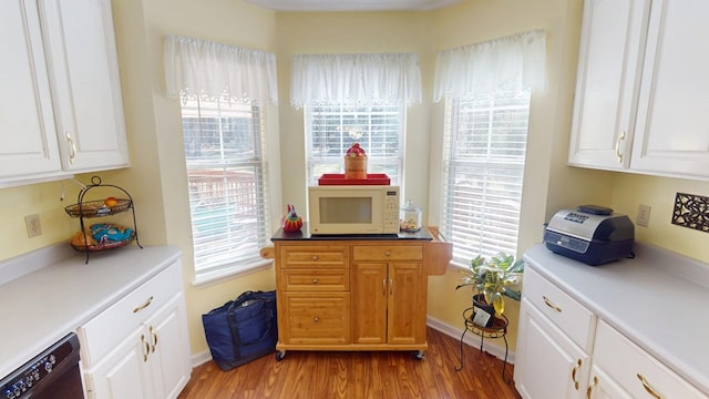 kitchen featuring dishwasher, white microwave, light wood-type flooring, and white cabinets