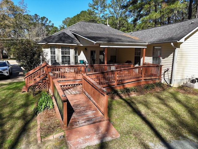 exterior space featuring a shingled roof, a deck, and a lawn