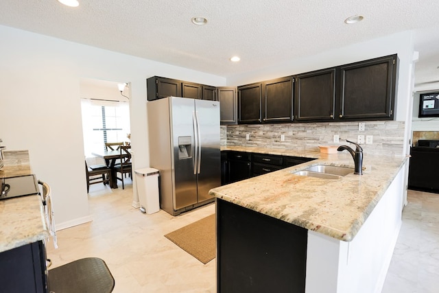 351 Plantation Ln, Thomasville, GA 31757 - kitchen featuring stainless steel refrigerator with ice dispenser, backsplash, a peninsula, light stone counters, and a textured ceiling