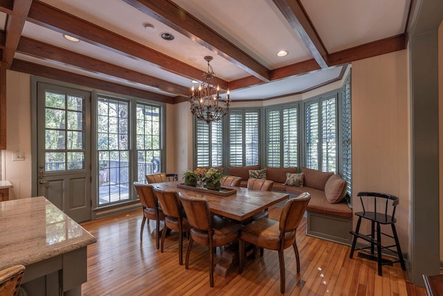 dining area with beamed ceiling, an inviting chandelier, and light hardwood / wood-style floors