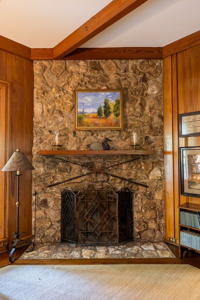 room details with beamed ceiling, a stone fireplace, and carpet